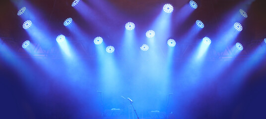 An empty stage - evoking anticipation. A stage at a music festival with lights streaming down from...