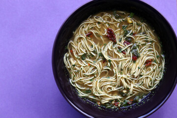 Top view of an asian noodle soup on a purple background 