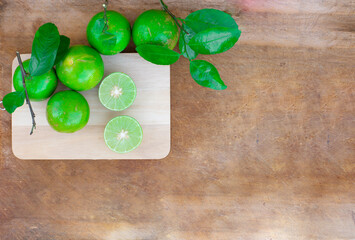 Fresh lime (lemon) and green leaf on wooden cutting board. Wooden background.