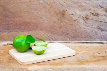 Fresh lime (lemon) and green leaf on wooden cutting board. Wooden background.