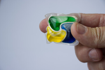 Single dishwasher detergent tablet in hand on white background