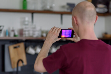Person doing thermal scanning or imaging of apartment with smartphone app. Thermographic Inspection to check effectiveness of insulation