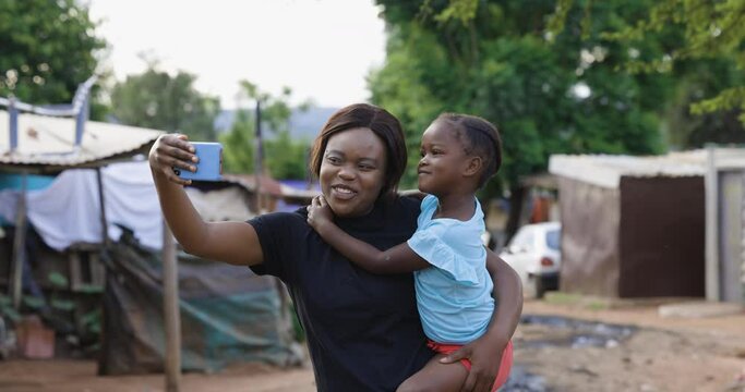 Black African Lesbian woman with her cute daughter taking a selfie in an informal settlement slum