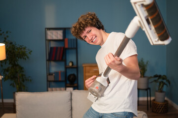 Portrait of a young boy enjoying an evening of cleaning with a smile. A teenager holds a vacuum...