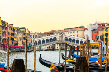 Row of gondolas on Grand Canal with Ponte Rialto on background.