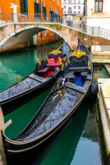 Fototapeta na wymiar Two traditional venetian gondolas docked near the bridge in Venice, Italy