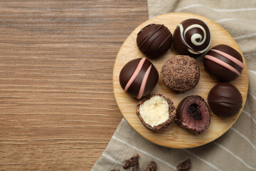 Many different delicious chocolate truffles on wooden table, top view. Space for text