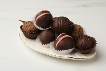 Different delicious chocolate truffles on white marble table