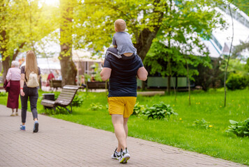 Father with her son walking in the summer Park
