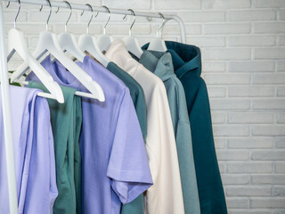 Lilac and green T-shirt, sweatpants, sweatshirt. Women's, youth clothes of different colors hang on...