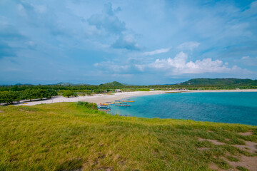 White sand beach and gentle waves with stunning green hills on the South side of Lombok Island, Indonesia