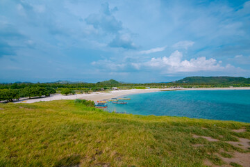 Fototapeta na wymiar White sand beach and gentle waves with stunning green hills on the South side of Lombok Island, Indonesia
