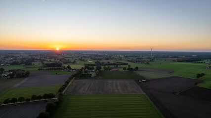 Aerial view of a rural landscape during sunrise in Belgium. Rural farm, corn fields, green fields, sunlight and fog. Belgium, Europe. High quality photo