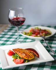 Grilled chicken breast with cherry tomatoes, green French beans, garlic, herbs, served on a white plate