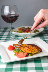 Grilled chicken breast with cherry tomatoes, green French beans, garlic, herbs, served on a white plate