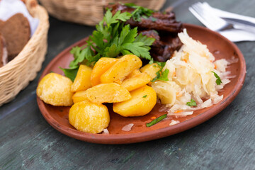 Bavarian baked pork ribs with boiled potatoes and sauerkraut closeup