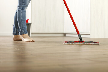 Woman legs and red mop in home interior. 