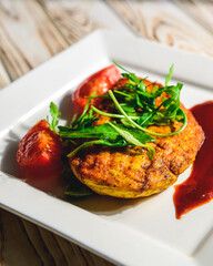 Grilled chicken breast with cherry tomatoes, green French beans, garlic, served on a white plate over wooden table.