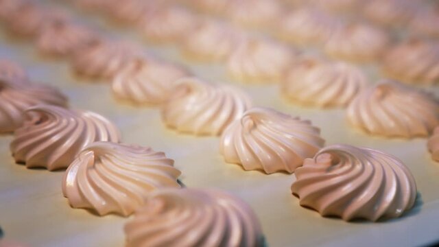 Conveyor belt with freshly-made sweet marshmallows. Close look at the creamy desserts. Blurred background.
