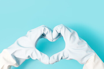 Female hands in gloves in the shape of a heart on blue background.