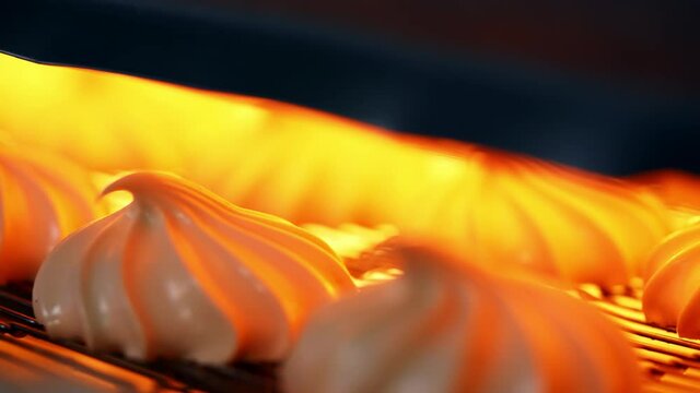 Marshmallow candies go under the drier on conveyor grid. Close up. Automated manufacturing of sweets at modern factory.