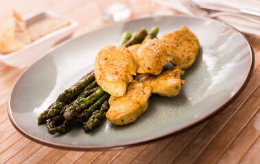 cooked dish. Chicken nuggets with green asparagus on plate