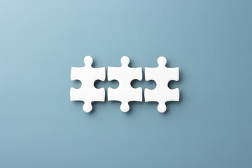white jigsaw puzzle pieces on blue paper background with copy space 