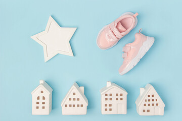 Fototapeta na wymiar Pink sneakers and white ceramic houses on a blue background. Creative sport concept. Top view Flat lay