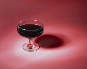 Red wine in glass on red content background with copy space