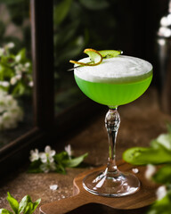 Kiwi Qaiquiri cocktail with fresh kiwi slice on brown background and windows behind. Spring brunch drink ideas. summer party