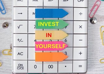 invest in yourself text is written on the stickers that are on the calculator