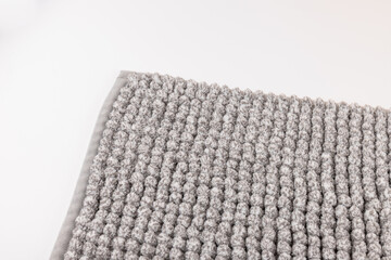 Soft grey bath mat against white background, closeup.Bath Accessories. Top view.