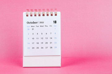 October 2022 desk calendar on pink background.