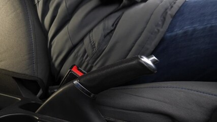 The man gets into the car, fastens his seat belt and disengages the parking brake. The concept of safe car use.