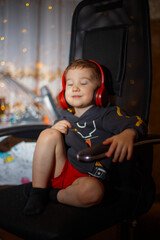 little boy 5 years old listening to music with headphones sitting in a chair
