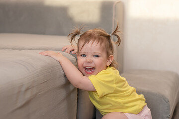 Funny one year old child playing at home in a yellow t-shirt.