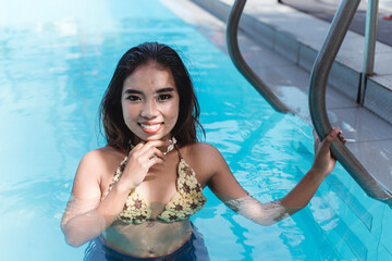 A young and attractive Filipina in a Crochet Bikini top and shorts taking a dip at a swimming pool....