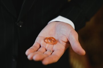 The groom on his wedding day holds two wedding rings in his hand in a hotel room. The man is...
