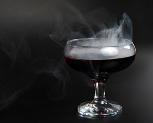 Red beverage cocktail with fume on black background with copy space