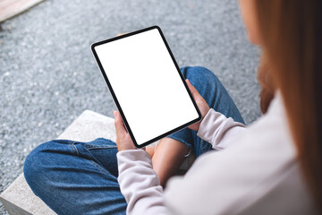 Mockup image of a woman holding digital tablet with blank white desktop screen in the outdoors