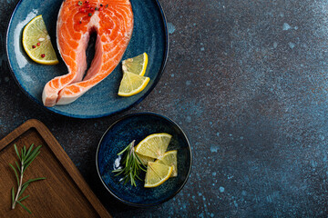 Uncooked raw fresh fish salmon steak top view on plate rustic dark concrete stone background with...