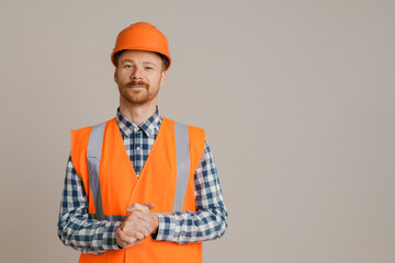 White man worker wearing helmet and vest looking at camera