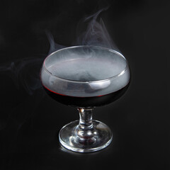 Red beverage cocktail with fume on black background with copy space