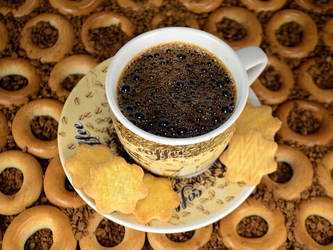 A cup of coffee with cookies on the background of small bagels. © Andrey