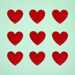 Pattern made of bold red heart shape on pastel green background. Cute minimal Valentine's day  inspiration for romantic Holiday.