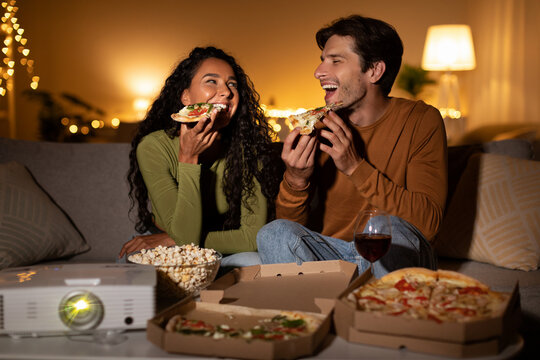 Couple Eating Pizza Watching Film Using Home Cinema Projector Indoor