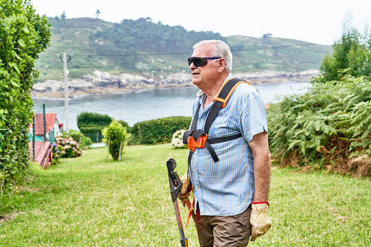 Senior man gardener with garden instrument in grassy lawn