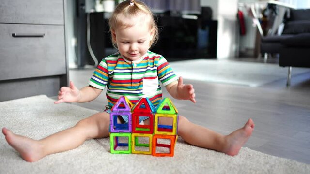 Little girl playing colorful magnet plastic blocks kit at home. The child playing educational games. Early childhood development.