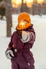 Fototapeta na wymiar cute girl keeps a sparkler in winter in the forest