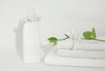 Spa composition with white towels, bottles and containers on the table, spa set.Cosmetics and cotton towels with a green plant on a white table inside the bathroom. Space for text.
